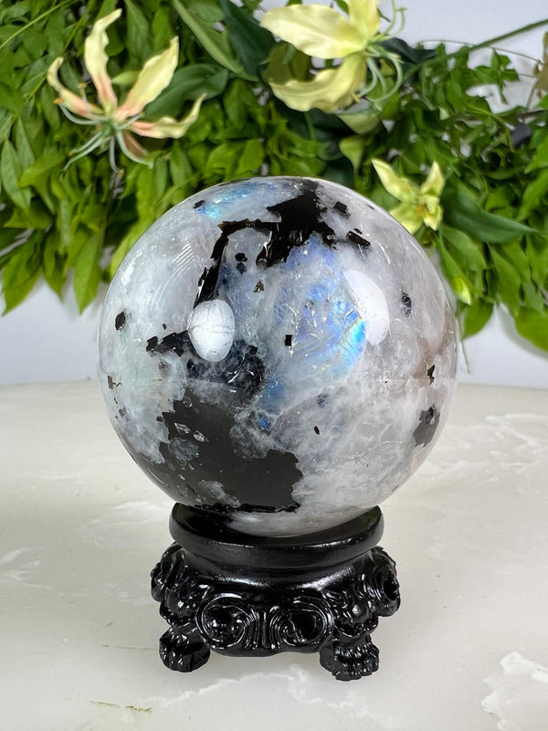Voorkant maansteen bol 2 met blauwe flash op zwarte bolhouder design met pootjes.